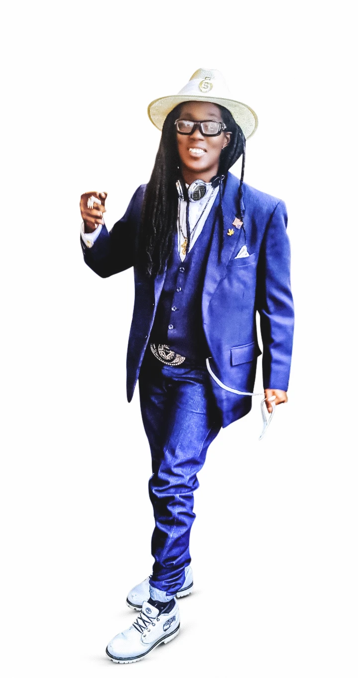 Smiling Ashton Smith, with long black dreds, emphasizing a point with his right hand, wearing a royal blue suit and vest, white shirt, white hat, large silver belt buckle, and headphones.